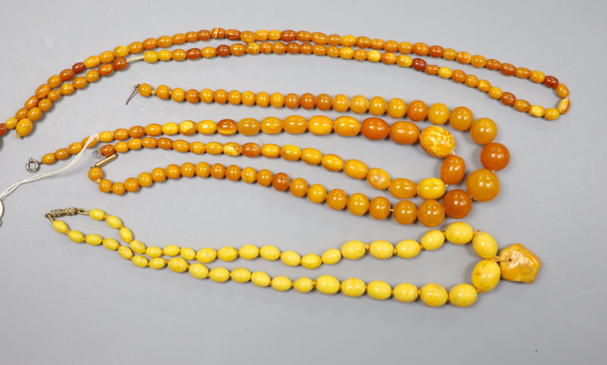 Four assorted single strand amber bead necklaces, largest 62cm, gross weight 86 grams.